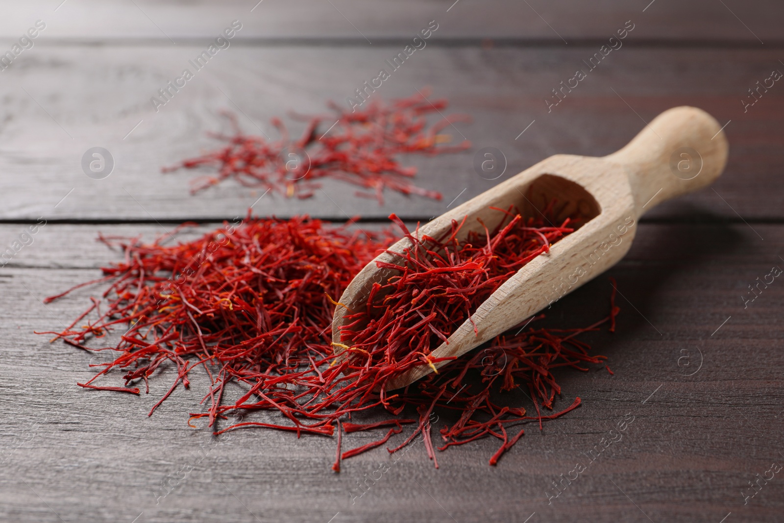 Photo of Dried saffron and scoop on wooden table
