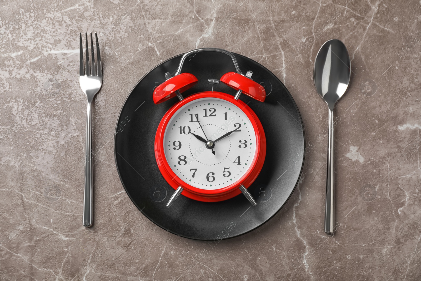 Photo of Flat lay composition with alarm clock, plate and utensils on grey background