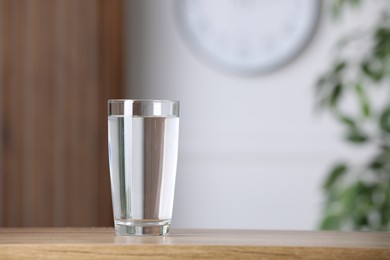 Photo of Glass of pure water on wooden table indoors. Space for text
