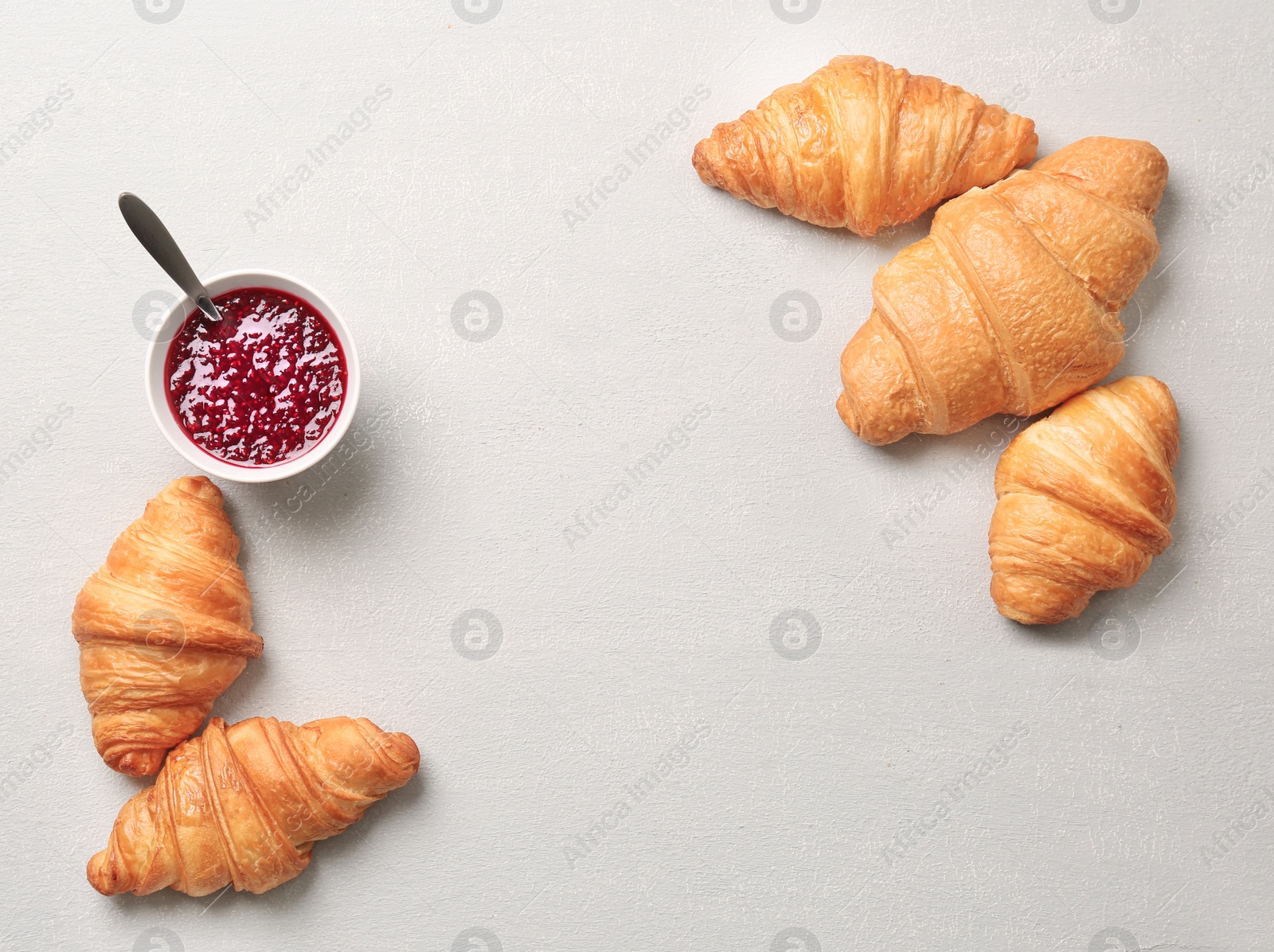 Photo of Tasty croissants with jam on light background, top view
