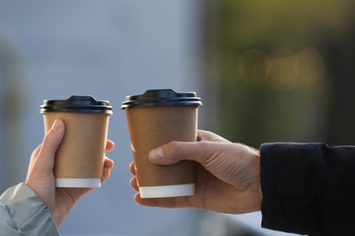Photo of Couple with takeaway coffee cups outdoors, closeup