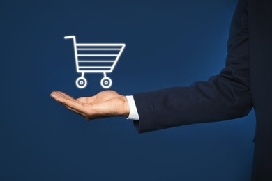 Image of Man demonstrating virtual image of shopping cart on blue background, closeup