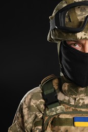 Photo of Soldier in Ukrainian military uniform with tactical goggles and balaclava on black background, closeup