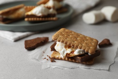 Photo of Delicious marshmallow sandwiches with crackers and chocolate on light grey table, closeup
