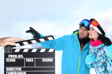 Image of Assistant holding clapperboard and couple at mountain resort, closeup. Cinema production 