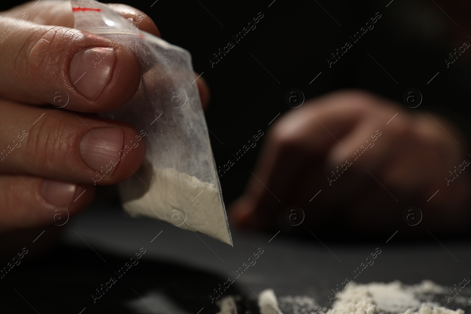 Photo of Addicted man with plastic bag of hard drug on blurred background, selective focus. Space for text