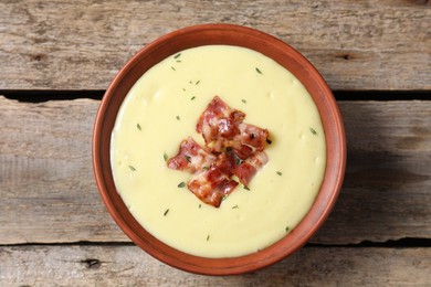 Tasty potato soup with bacon and rosemary in bowl on wooden table, top view