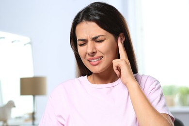 Photo of Young woman suffering from ear pain indoors
