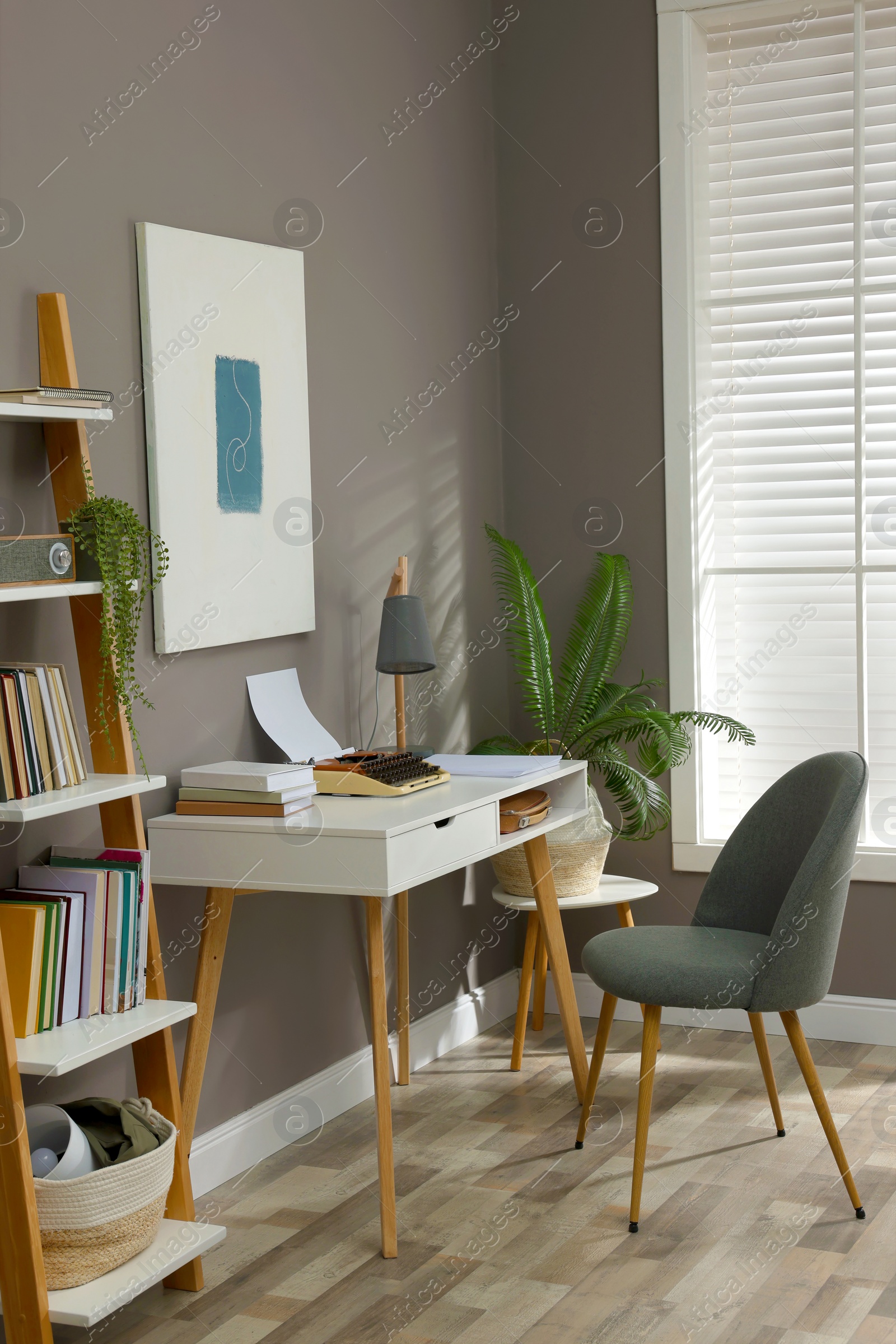 Photo of Comfortable writer's workplace interior with typewriter on desk near grey wall