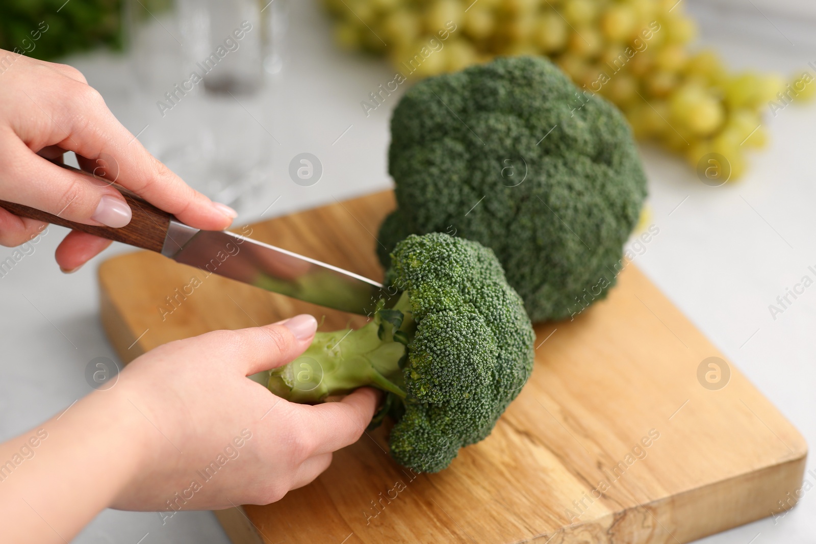 Photo of Woman cutting broccoli for smoothie at table, closeup