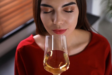 Photo of Beautiful young woman with glass of luxury white wine indoors, closeup view