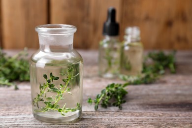 Photo of Thyme essential oil and fresh plant on wooden table, closeup. Space for text