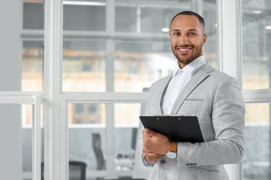 Photo of Happy man with clipboard in office, space for text. Lawyer, businessman, accountant or manager