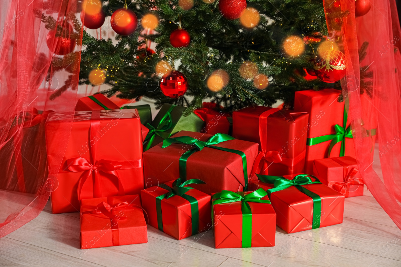 Photo of Beautifully wrapped gift boxes under Christmas tree indoors