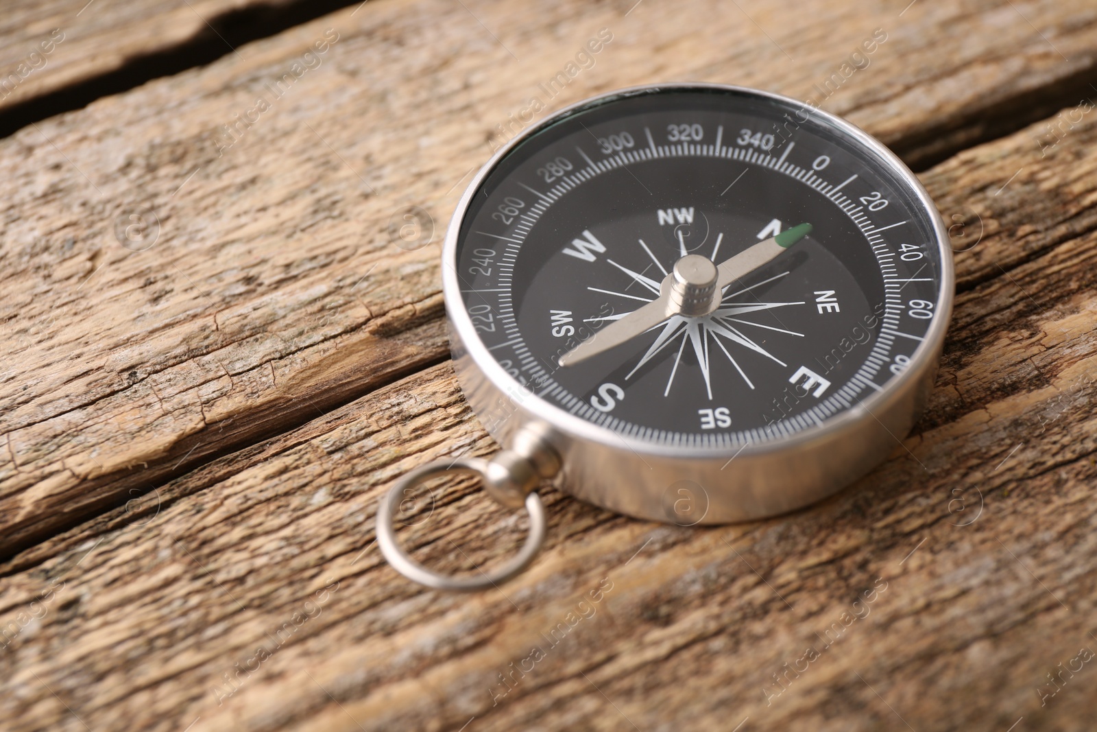 Photo of One compass on wooden table, space for text. Tourist equipment