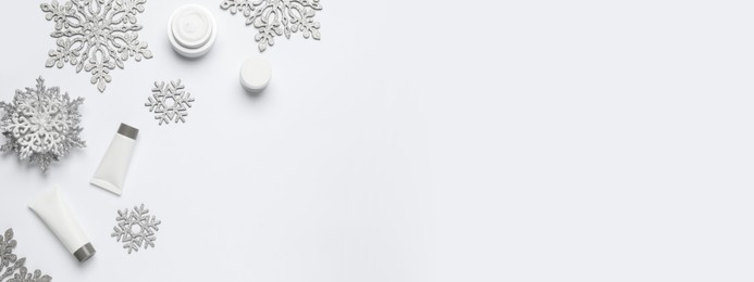 Image of Winter skin care. Composition with cosmetic products and snowflakes on white background, top view. Banner design