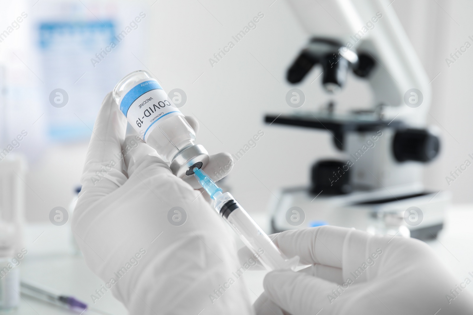 Photo of Doctor filling syringe with vaccine against Covid-19 indoors, closeup