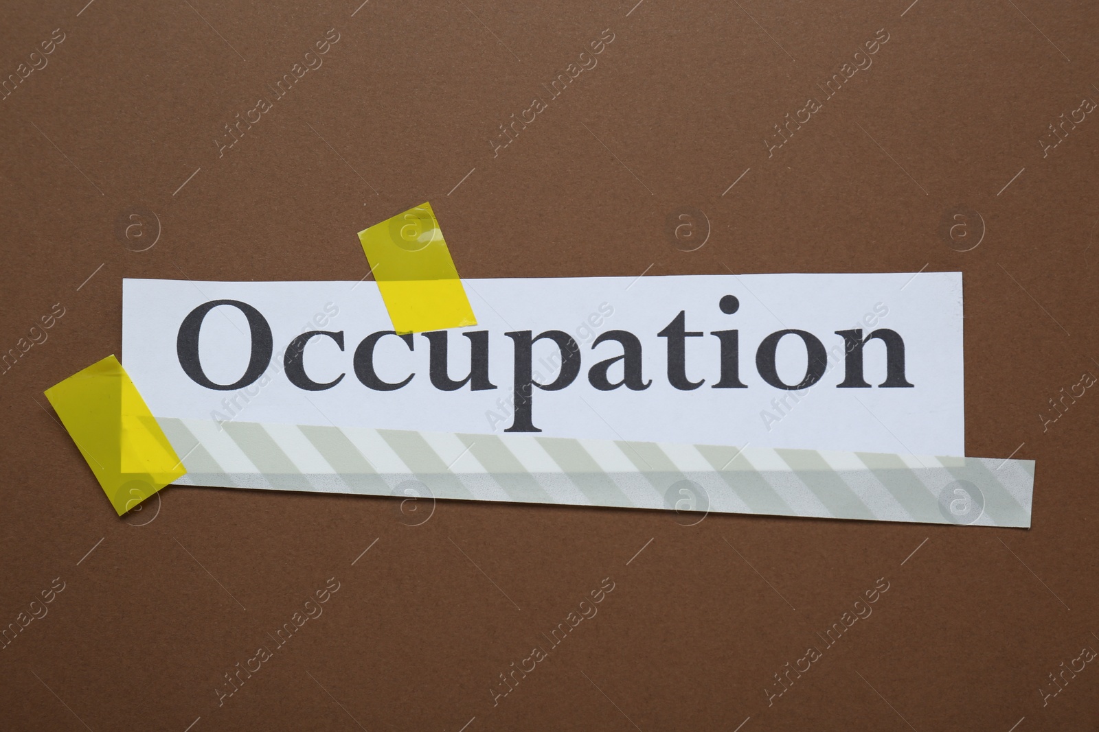 Photo of Word Occupation attached with yellow adhesive tape on brown background