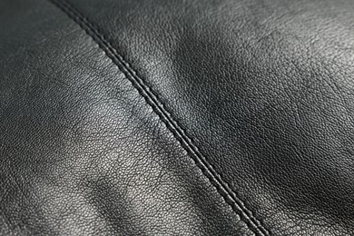 Black natural leather with seams as background, closeup view