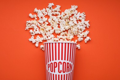 Photo of Bucket of tasty popcorn on orange background, flat lay