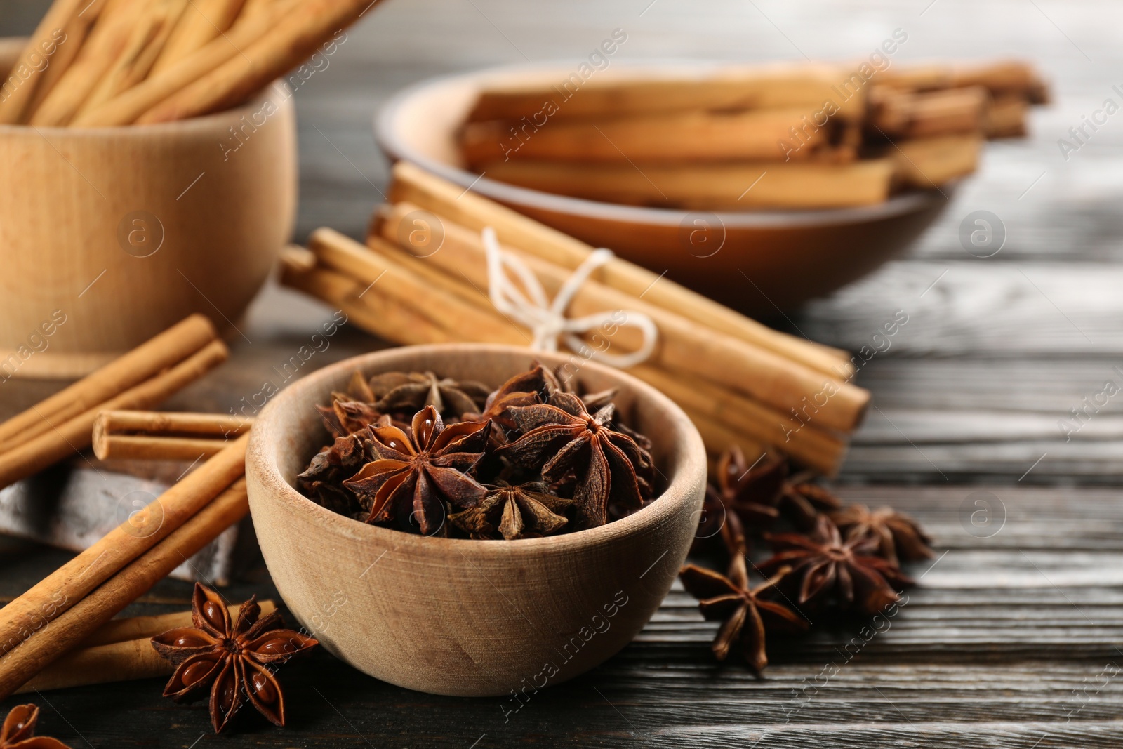 Photo of Aromatic cinnamon sticks and anise on wooden table, closeup