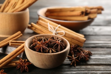 Photo of Aromatic cinnamon sticks and anise on wooden table, closeup