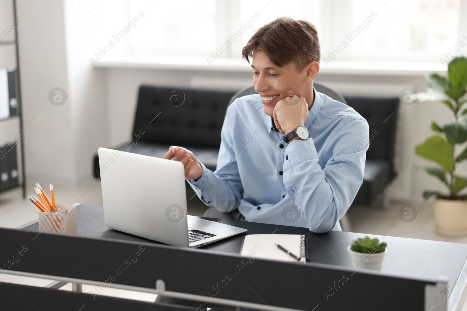 Photo of Man using video chat during webinar at table in office