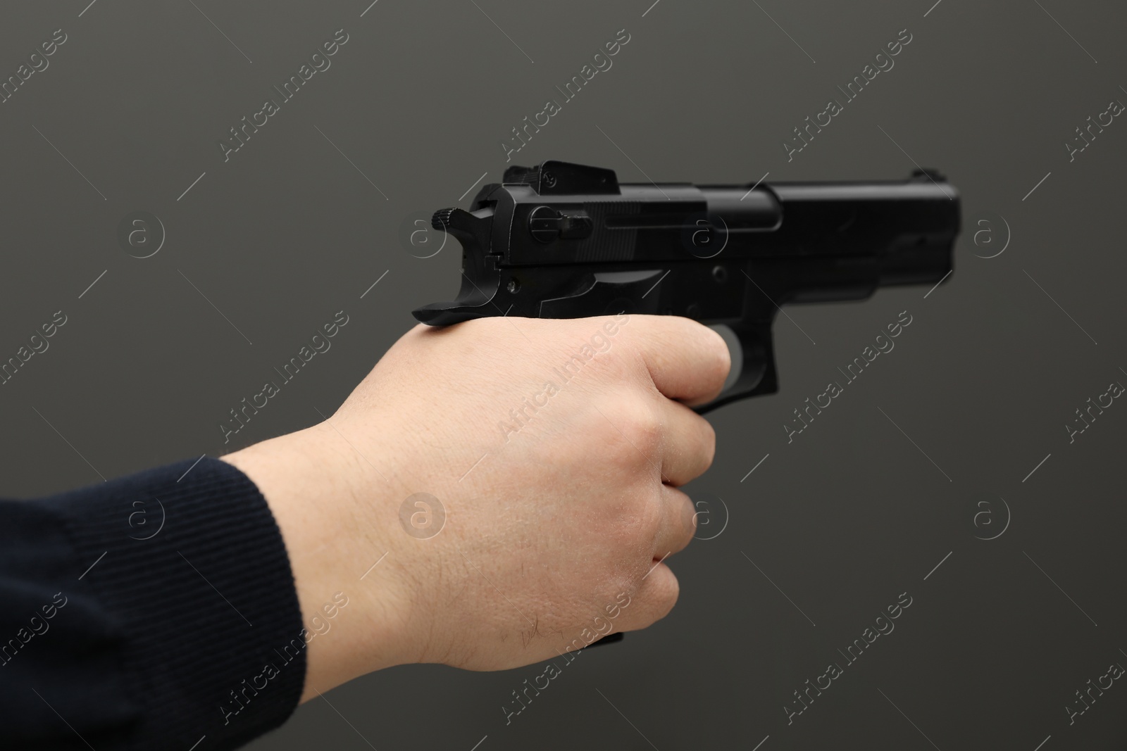 Photo of Man with handgun on dark gray background, closeup