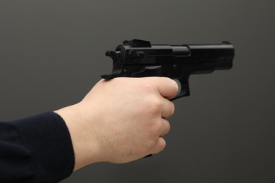 Photo of Man with handgun on dark gray background, closeup
