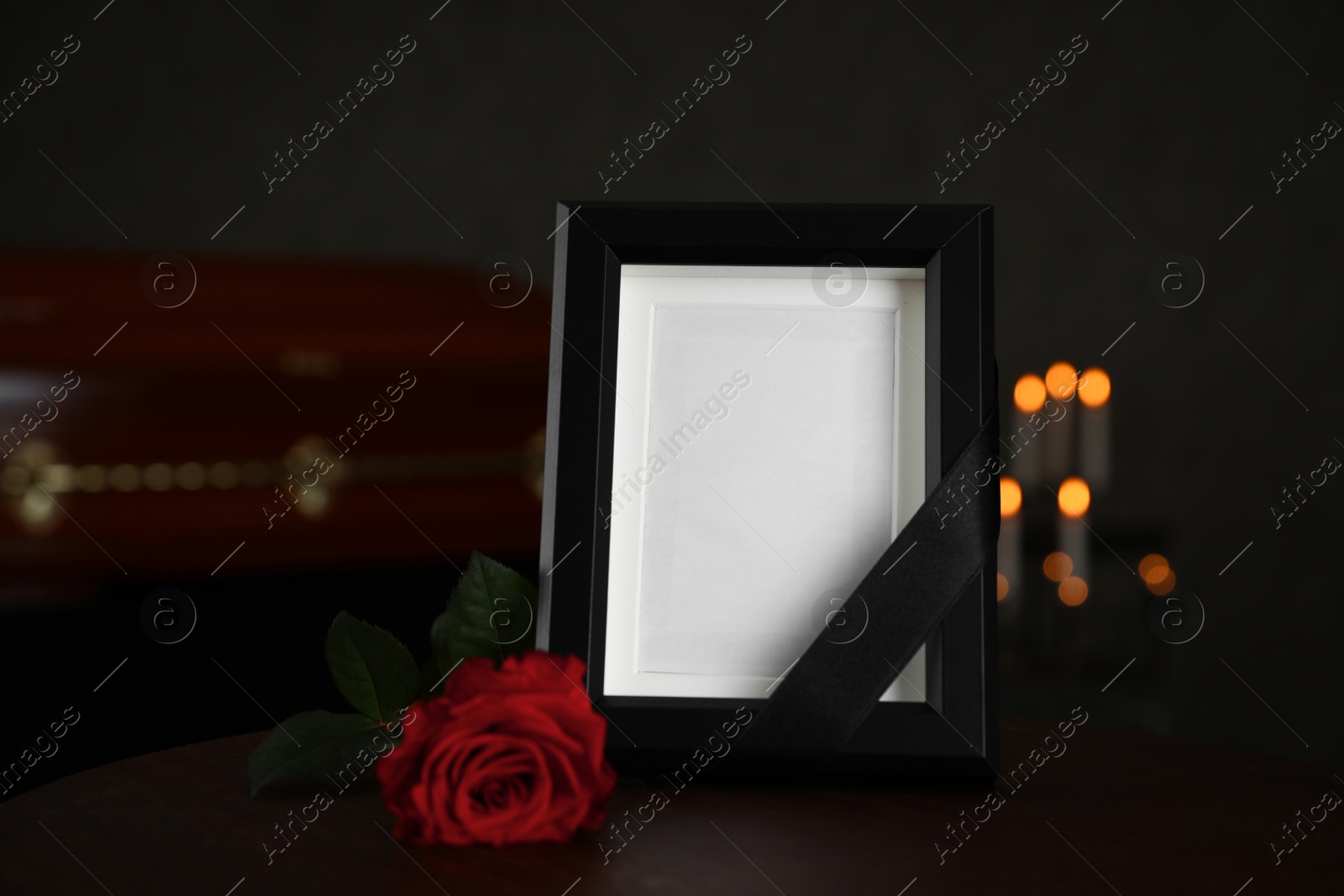 Photo of Black photo frame and red rose on table in funeral home