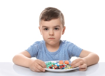 Photo of Little child with plate of pills on white background. Household danger