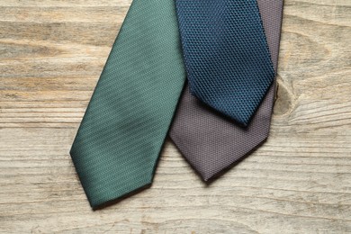 Photo of Different neckties on light wooden table, flat lay