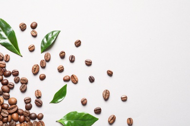 Photo of Fresh green coffee leaves and beans on light background, flat lay. Space for text
