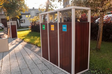 Photo of Different sorting bins for waste recycling on sunny day outdoors