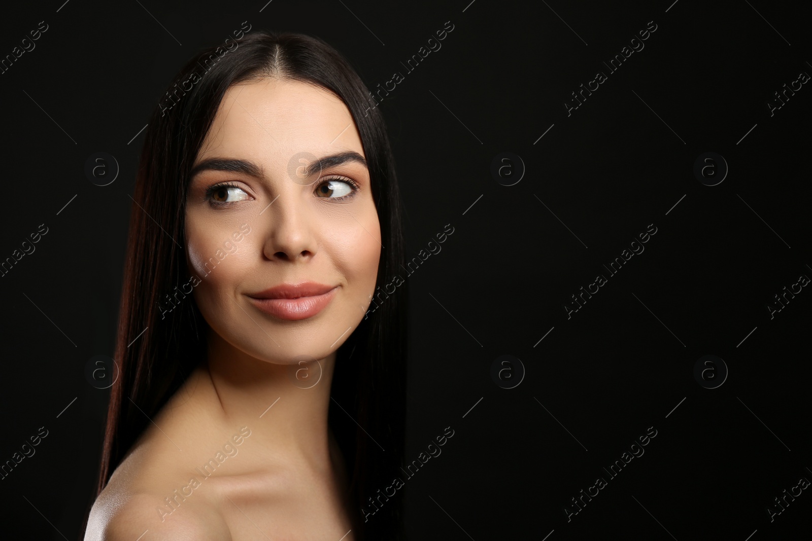 Photo of Portrait of happy young woman with beautiful black hair and charming smile on dark background, space for text