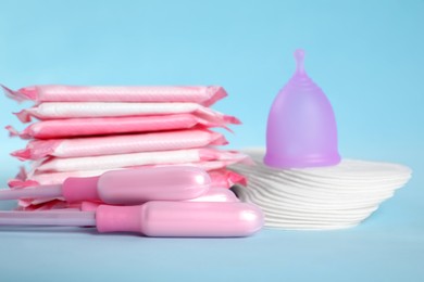 Photo of Menstrual pads and other hygiene products on light blue background, closeup