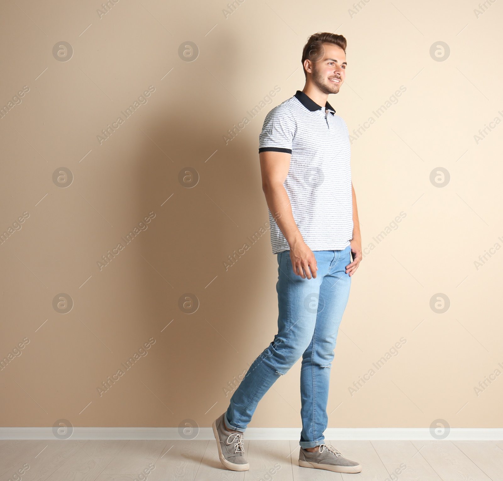 Photo of Young man in stylish jeans near light wall