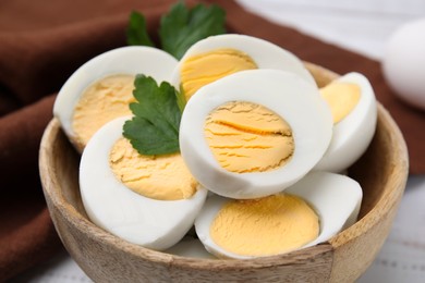 Photo of Wooden bowl with fresh hard boiled eggs and parsley on table, closeup