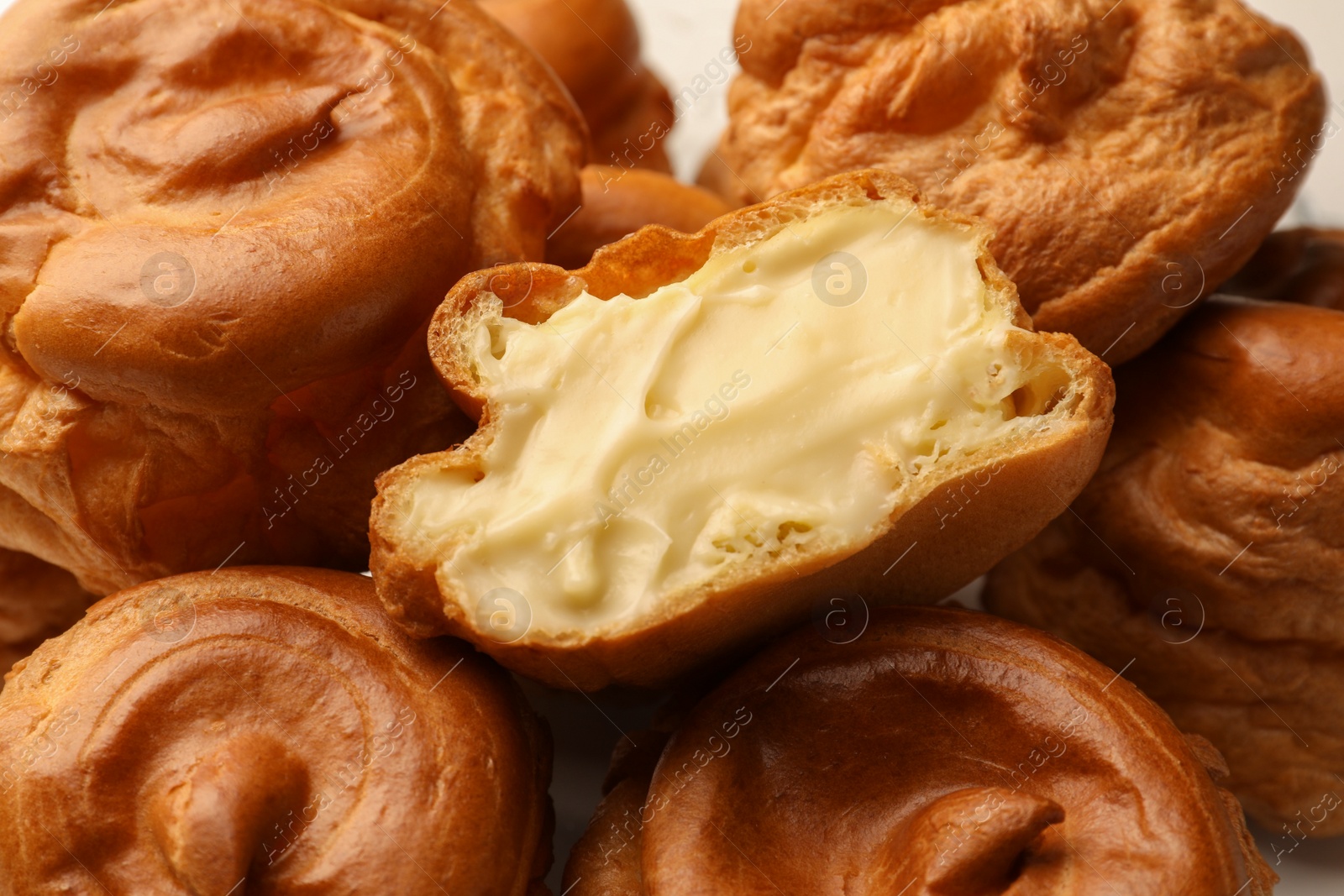 Photo of Delicious profiteroles with cream filling inside, closeup