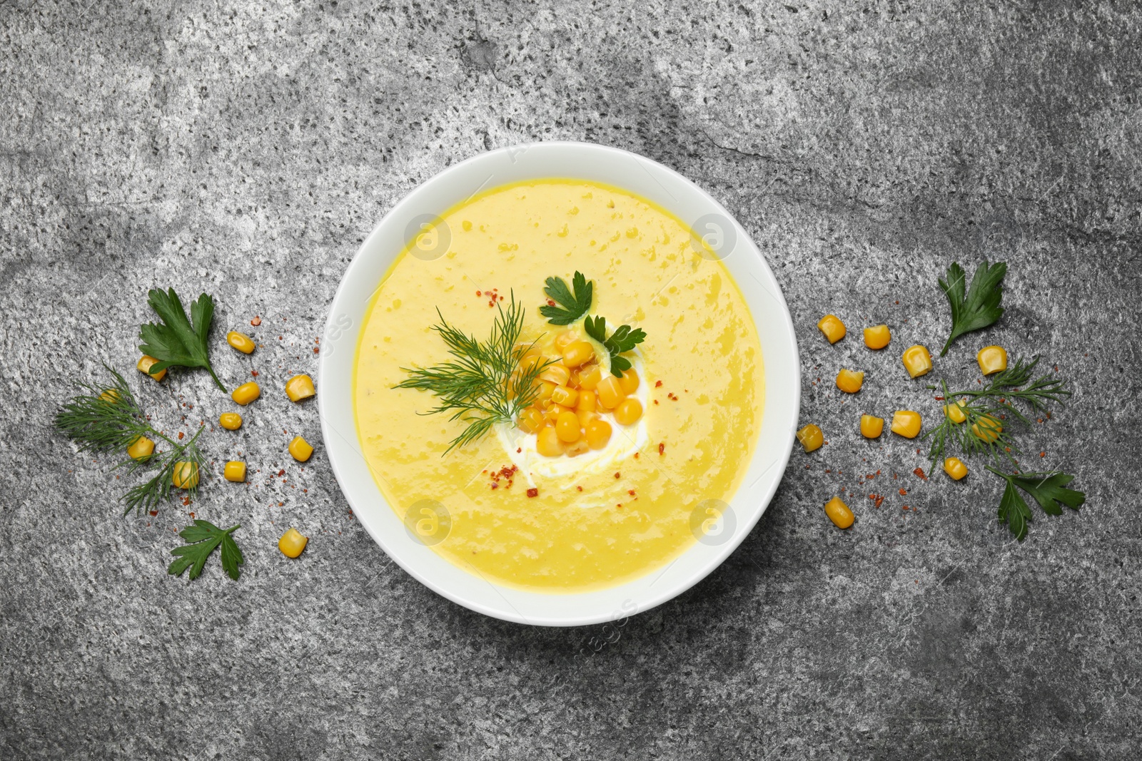 Photo of Delicious creamy corn soup served on grey table, flat lay