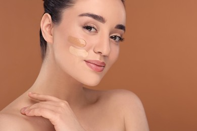 Photo of Woman with swatches of foundation on face against brown background