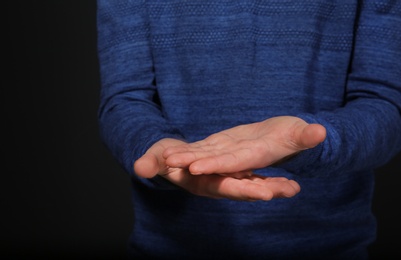 Photo of Man showing word GOOD in sign language on black background, closeup. Space for text