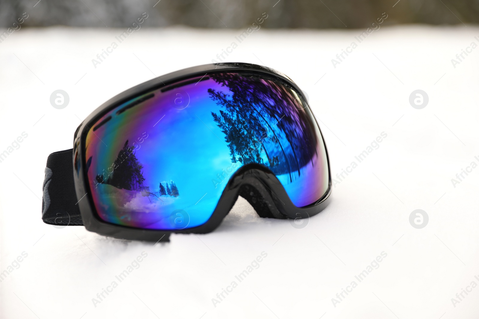 Photo of Stylish ski goggles on snow outdoors. Winter sport equipment