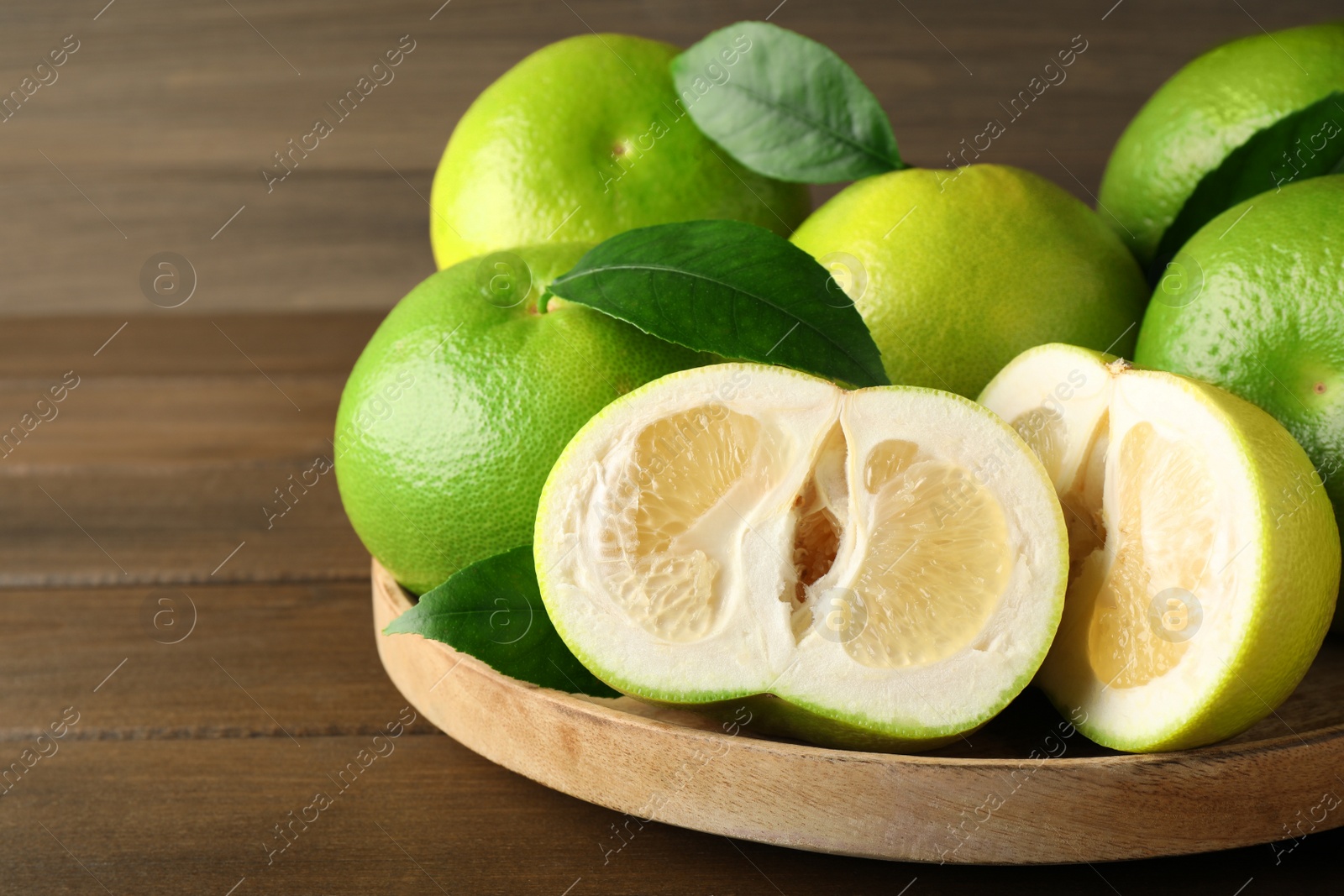 Photo of Whole and cut sweetie fruits on wooden table