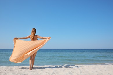 Photo of Woman with beach towel near sea on sunny day, back view