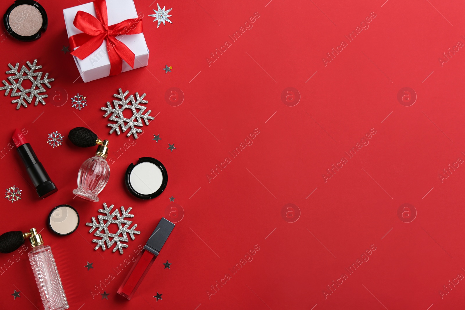 Photo of Flat lay composition with decorative cosmetic products on red background, space for text. Winter care