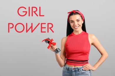 Image of 8 March greeting card. Phrase Girl Power and young woman holding dumbbell on light background