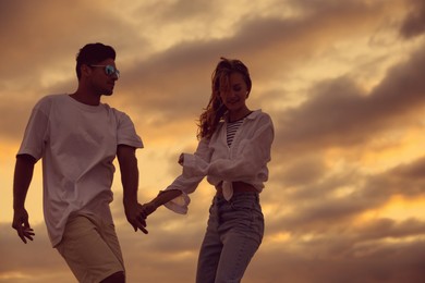 Happy couple dancing outdoors during beautiful sunset