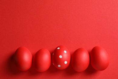 Photo of Flat lay composition of red painted Easter eggs on color background, space for text