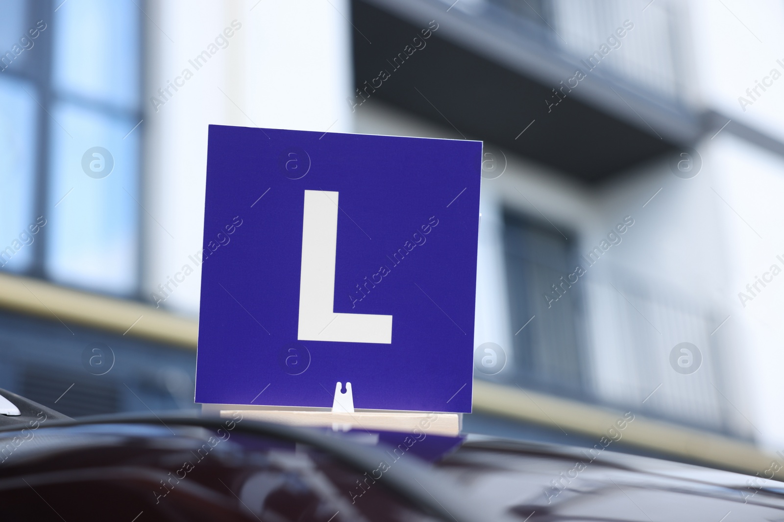 Photo of L-plate on car roof outdoors. Driving school